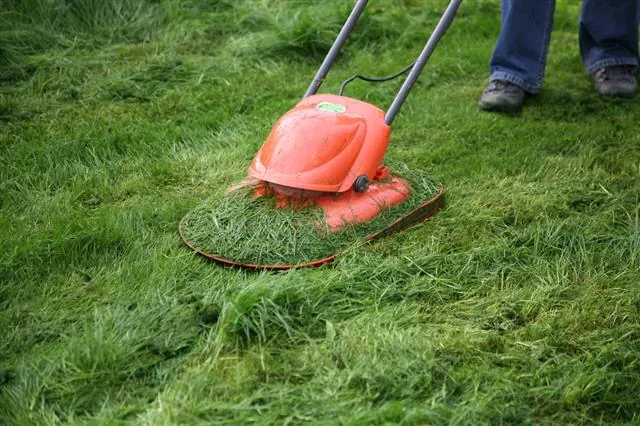 An orange hover lawn mower cutting grass on a green lawn.