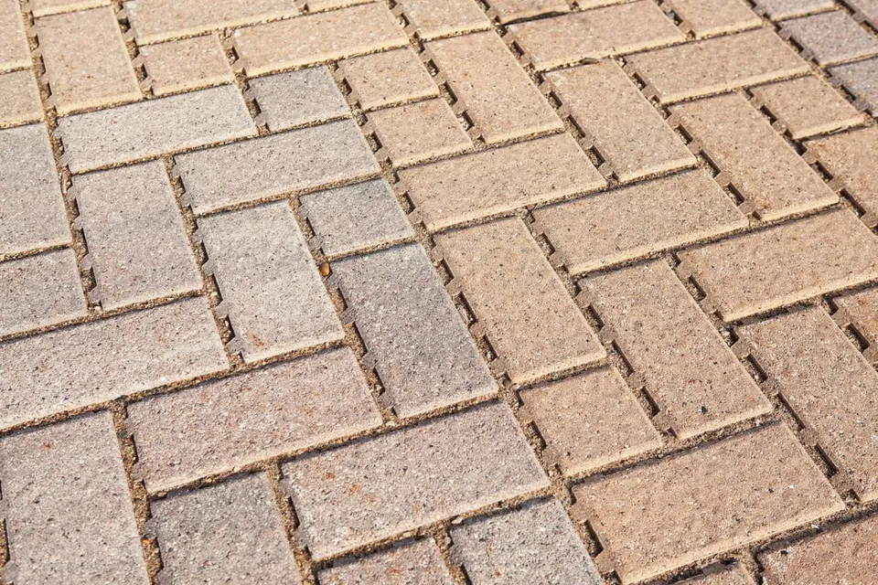 Close-up of interlocking grey and reddish-brown pavers laid in a herringbone pattern.