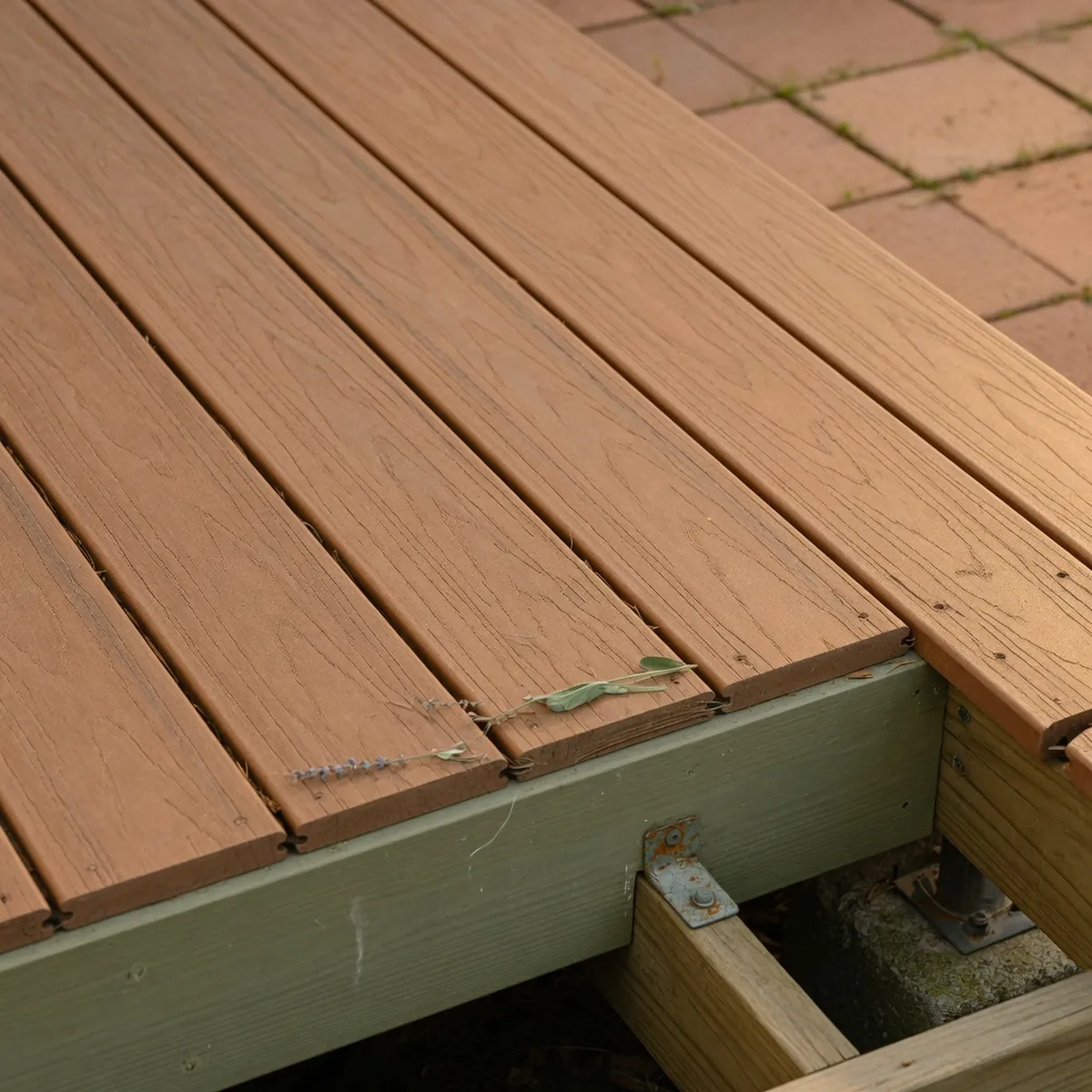 Interlocking composite decking planks with realistic wood grain texture rest on a patio frame.