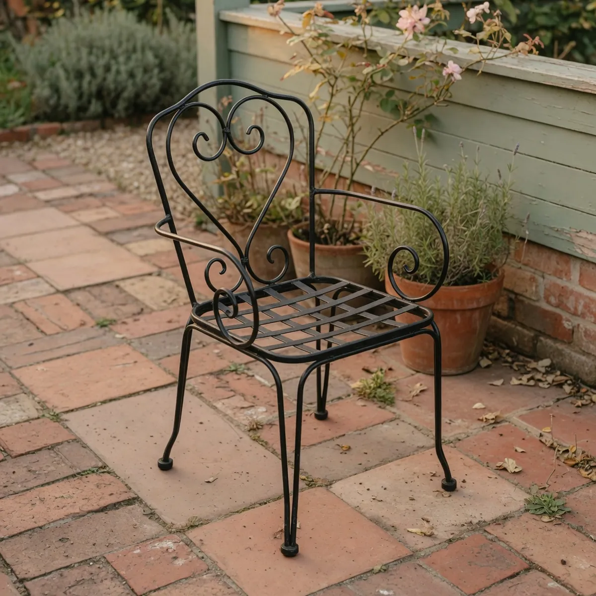 A black wrought iron chair with an open frame design resting on a paved patio.